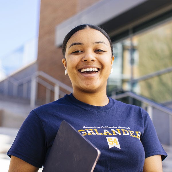 A female student smiling while outside on the UCR campus